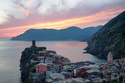 Townscape by sea against sky during sunset