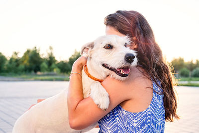 Close-up of woman embracing dog against clear sky