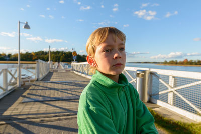 Portrait of boy on railing against sky