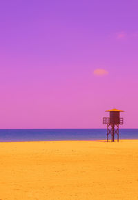 Lifeguard hut on beach against sky during sunset