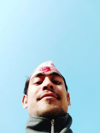 Low angle portrait of young man against clear blue sky