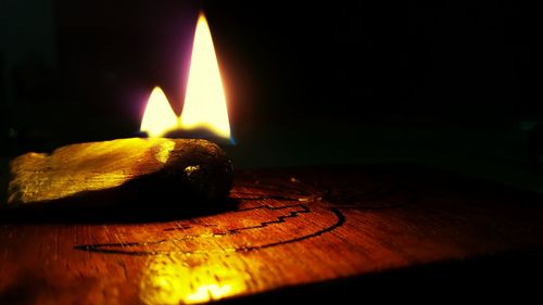 Close-up of burning candle on wooden surface