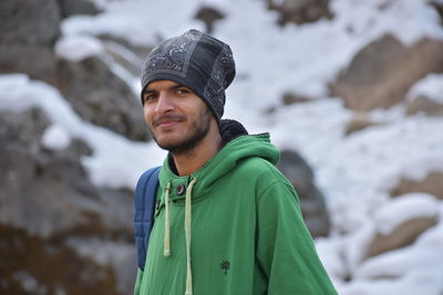 Portrait of smiling young man standing against mountain during winter