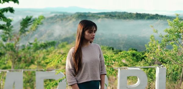 Young woman standing against mountains