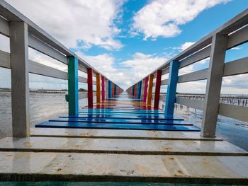 Empty walkway leading towards sea against sky