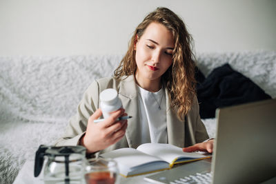 Young woman using mobile phone while sitting at table