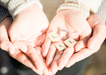 Cropped image of couple hands holding engagement ring with letter blocks