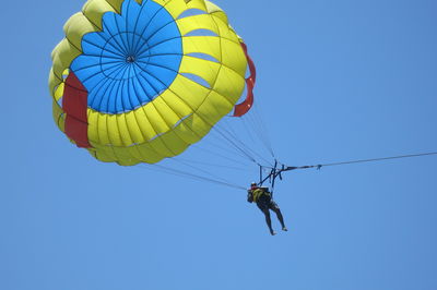 Low angle view of person parasailing against clear blue sky