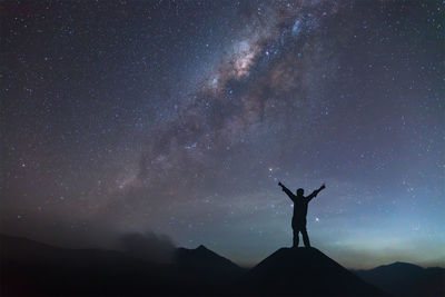 Low angle view of silhouette man standing against star field at night