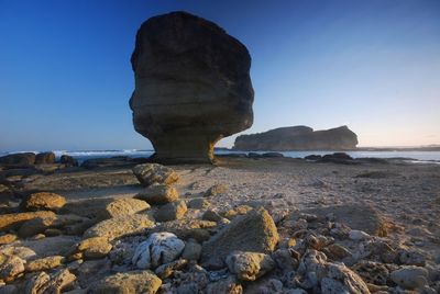 Rock formation on beach against clear sky