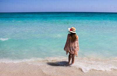 Rear view of woman standing at beach