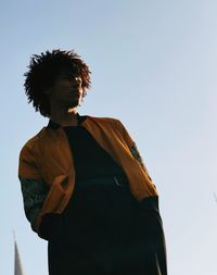 Low angle view of young man looking away against sky
