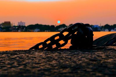 Close-up of chain on beach against sky during sunset