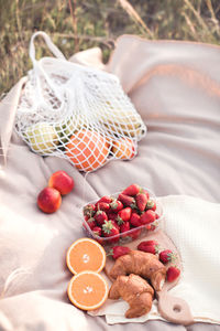 Picnic with fruits, strawberry and chocolate croissants on wooden tray outdoors closeup. 