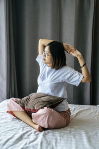 Young woman sitting on bed at home