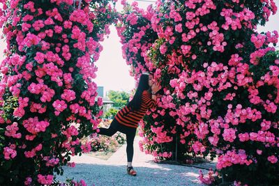 Side view of young woman smelling pink flowers at park