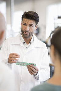 Male engineer explaining circuit board to business people in factory