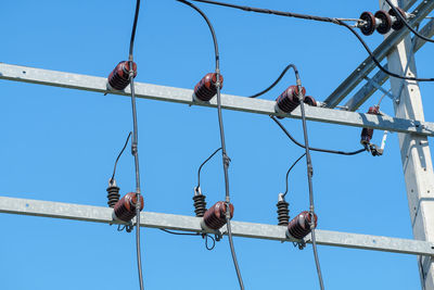 Low angle view of electricity transformer against clear blue sky