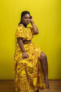 Young woman wearing colorful long clothes over yellow background. natural expression.