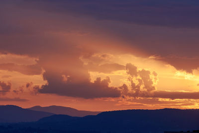 Scenic view of silhouette mountains against romantic sky at sunset