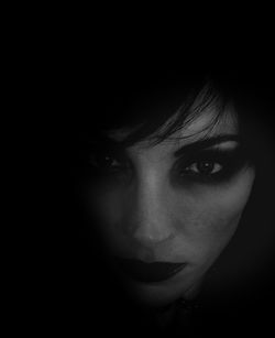 Close-up portrait of young woman against black background