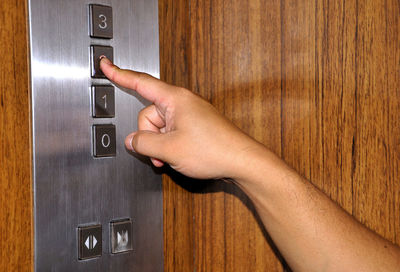 Close-up of hand pressing button in elevator