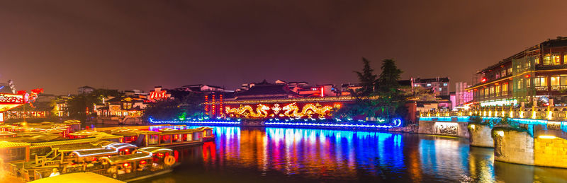 Illuminated bridge over river in city at night
