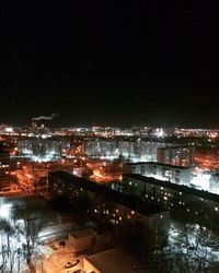 High angle view of illuminated buildings by lake against sky at night