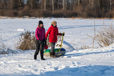 Female friends walking on snow covered field