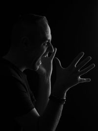 Portrait of man making face against black background