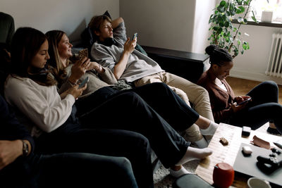 Teenage friends using social media on smart phones while sitting at home