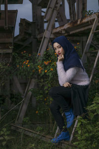 Portrait of young woman sitting by plants