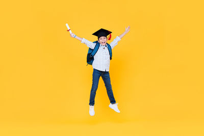Woman with umbrella standing against yellow background