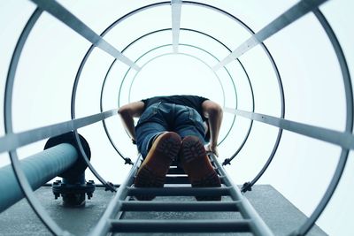 Low angle view of man climbing steps of building against sky