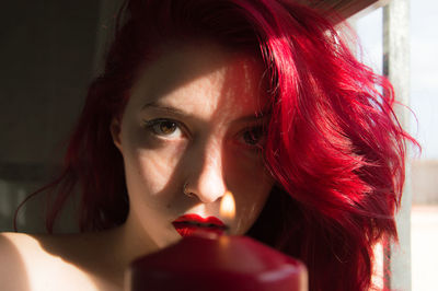 Portrait beautiful woman with dyed red hair by window at home