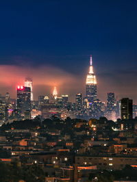 Illuminated buildings in city against sky at night