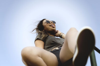 Low angle view of woman sitting against sky