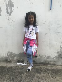 Portrait of girl standing against wall