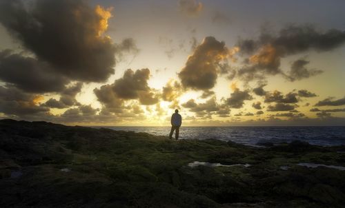 Man standing by sea against sky during sunset