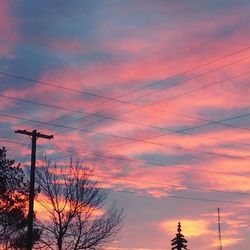 Low angle view of electricity pylon against cloudy sky