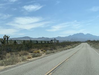 Empty road by landscape against sky