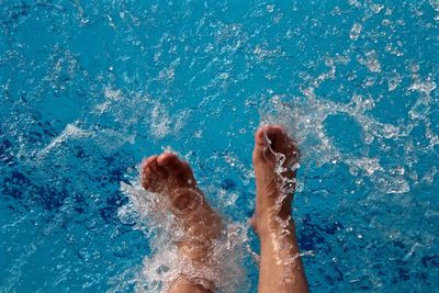 Low section of woman splashing water in swimming pool