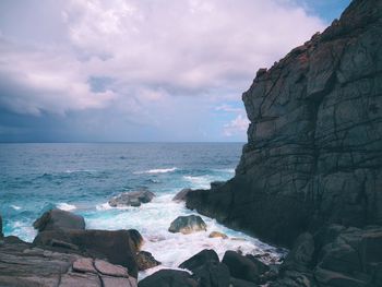 Rock formation by sea against sky