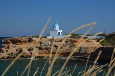 Lighthouse by building against clear blue sky