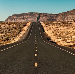 Road passing through desert against clear sky