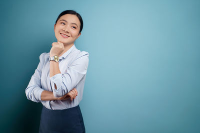 Portrait of a smiling young woman against blue background