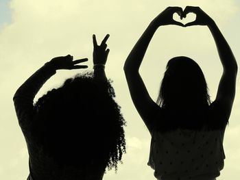 Rear view of silhouette friends against sky