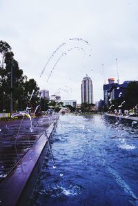 Water splashing in city against sky