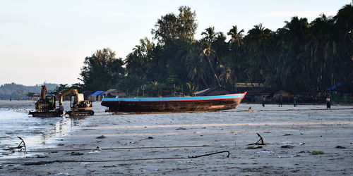 Boat moored on beach against sky