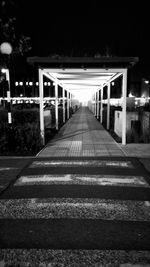 Empty footpath in illuminated city at night